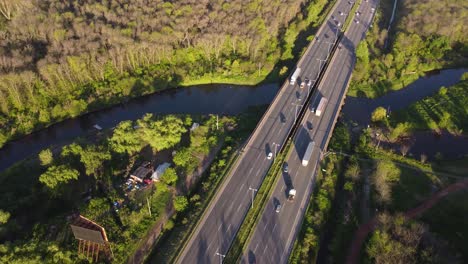 toma en órbita del movimiento del tráfico en la autopista pilar en buenos aires, argentina, rodeada de vegetación verde y recorriendo un arroyo