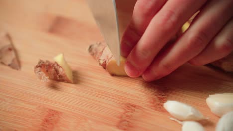 cutting ginger by hand with a knife on a cutting board