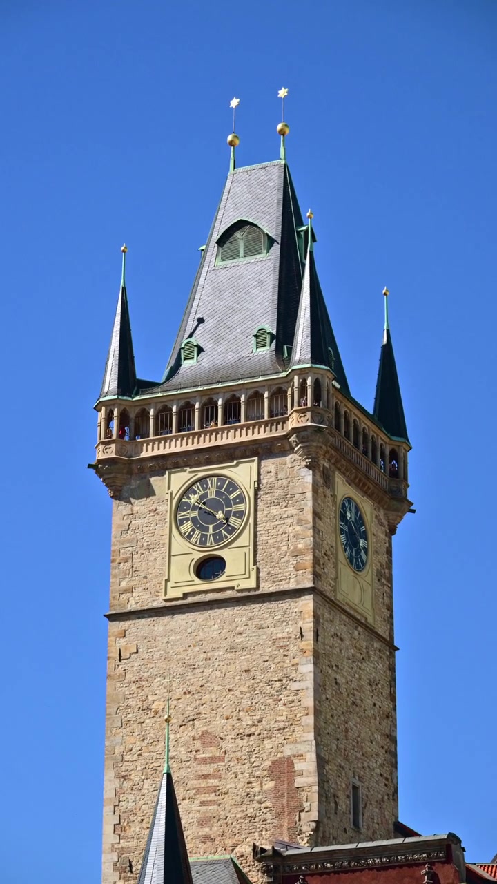 Vertical close view of the top of the Gothic Old Town Hall Tower with its clock against a clear blue sky, Prague, Czech Republic