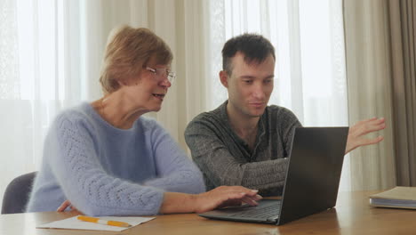 una mujer mayor y su hijo usando una computadora portátil juntos