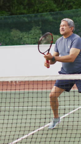 video de una feliz pareja de alto nivel biracial durante el entrenamiento en la cancha de tenis