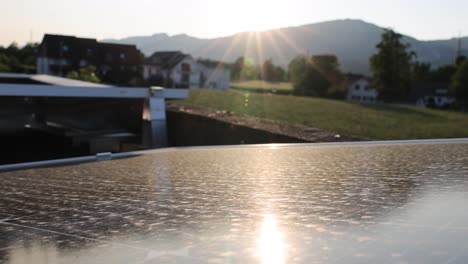 Dolly-shot-of-solar-panels-in-Austrian-countryside-with-sun-rays-behind-mountains-at-sunset---Production-of-sustainable-Energy-on-roof-of-house---close-up