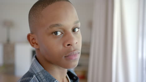 portrait of thoughtful african american male teenager with short hair at home, slow motion