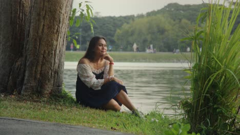 woman sitting by a lake in a park