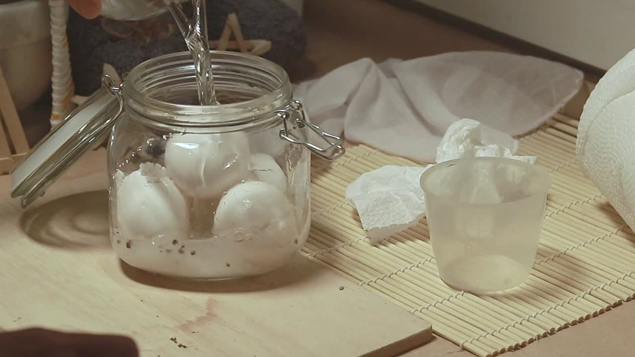 Adding sea salt and water to a mason jar containing raw eggs following a traditional recipe for making homemade salted eggs