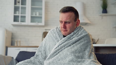 sick man covered with warm blanket. young man has a terrible headache and feeling ill at home. infected man with virus. coronavirus concept.