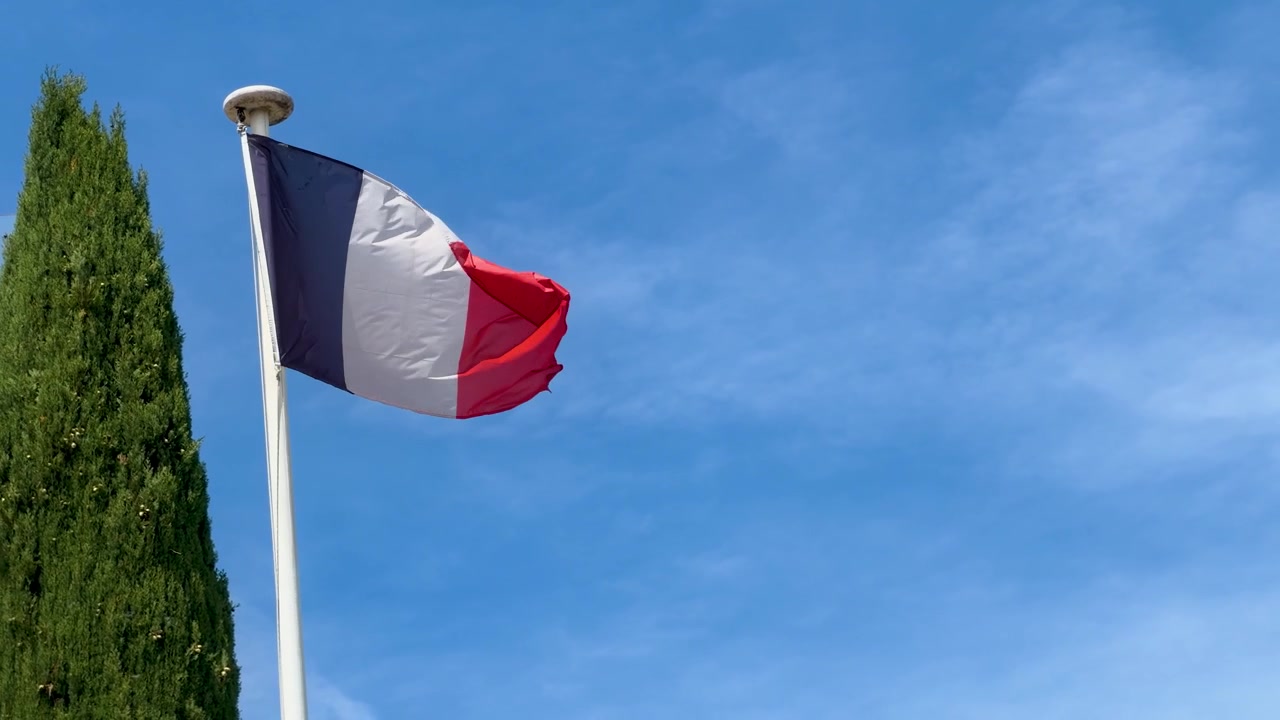La bandiera tricolore francese sventola su un'asta contro un cielo azzurro e limpido a Marsiglia