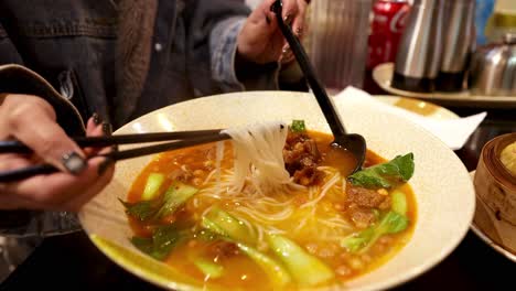 person enjoying ramen soup with chopsticks