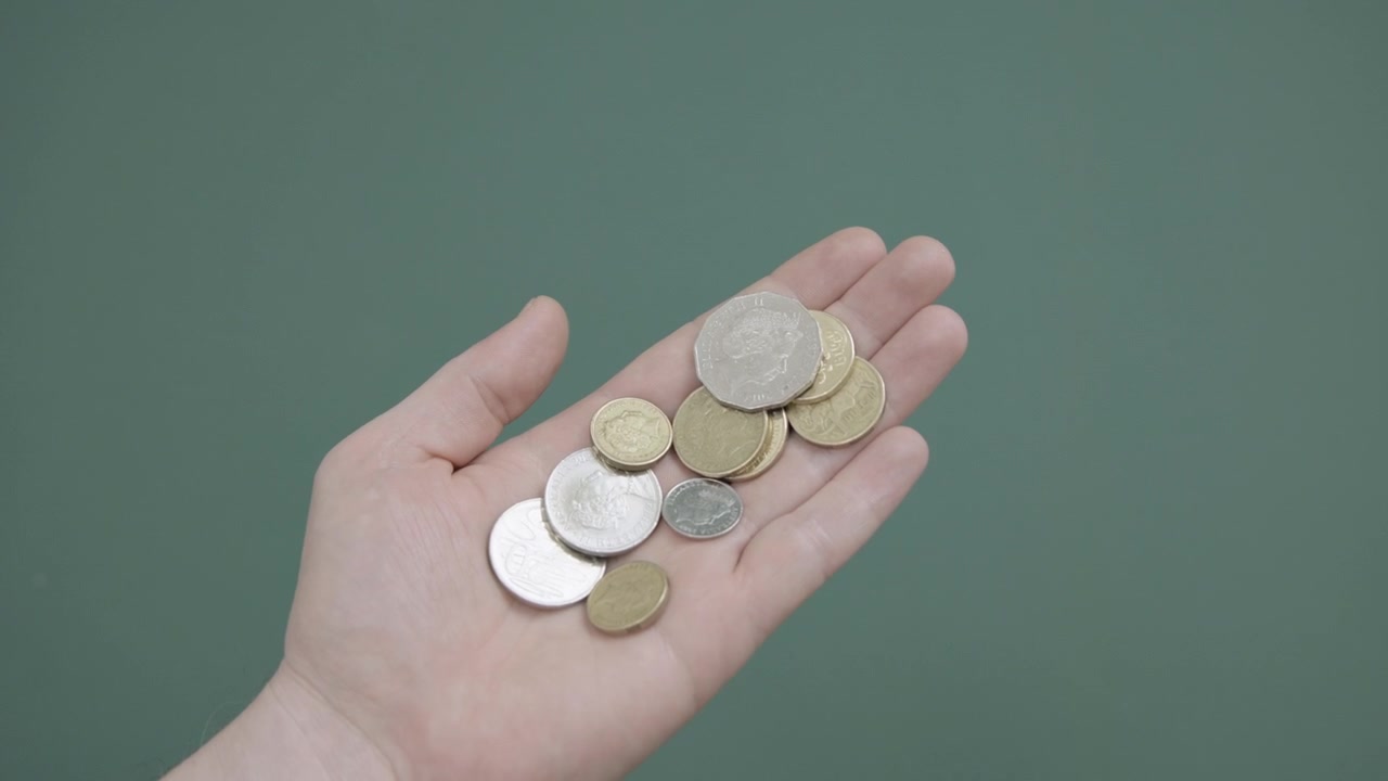 Una mano tiene una quantità di monete australiane mentre l'altra mano le conta e le ordina su schermo verde 4k.