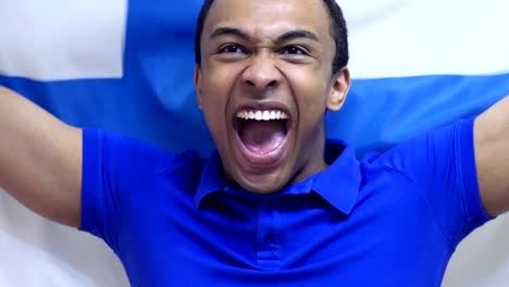 un aficionado finlandés celebra sosteniendo la bandera de finlandia en cámara lenta