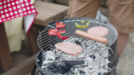 vertical motion of an unrecognizable man putting hamburger patties on grill