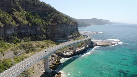 carretera al borde del acantilado con coches que viajan en verano en el puente del acantilado del mar en nueva gales del sur, australia