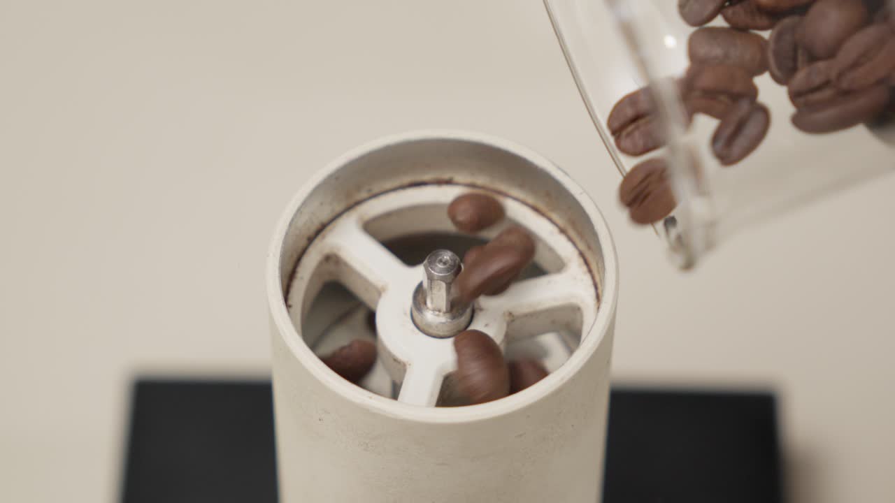 Pouring coffee beans into a grinder, slow-motion shot capturing the process