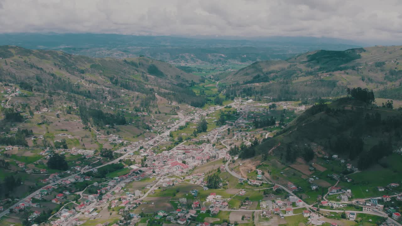 Aerial 4K drone shot flying backward over Cumbe, Ecuador, revealing the mountain village surrounded by Andean landscapes. Ideal for travel and rural documentary footage.