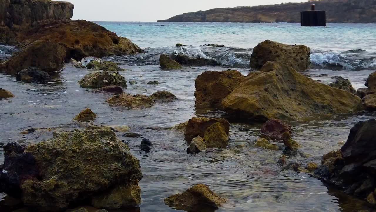Onde che si infrangono sulla riva, passando sopra le rocce per raggiungere la loro destinazione.