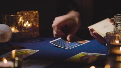 primer plano de una mujer dando una lectura de cartas del tarot en una mesa a la luz de las velas sosteniendo la carta de la muerte 4