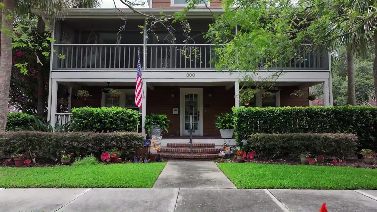 American single family house in noble neighborhood with proud flag at entrance. Beautiful spring day in Florida, USA. Aerial approaching tilt up shot.