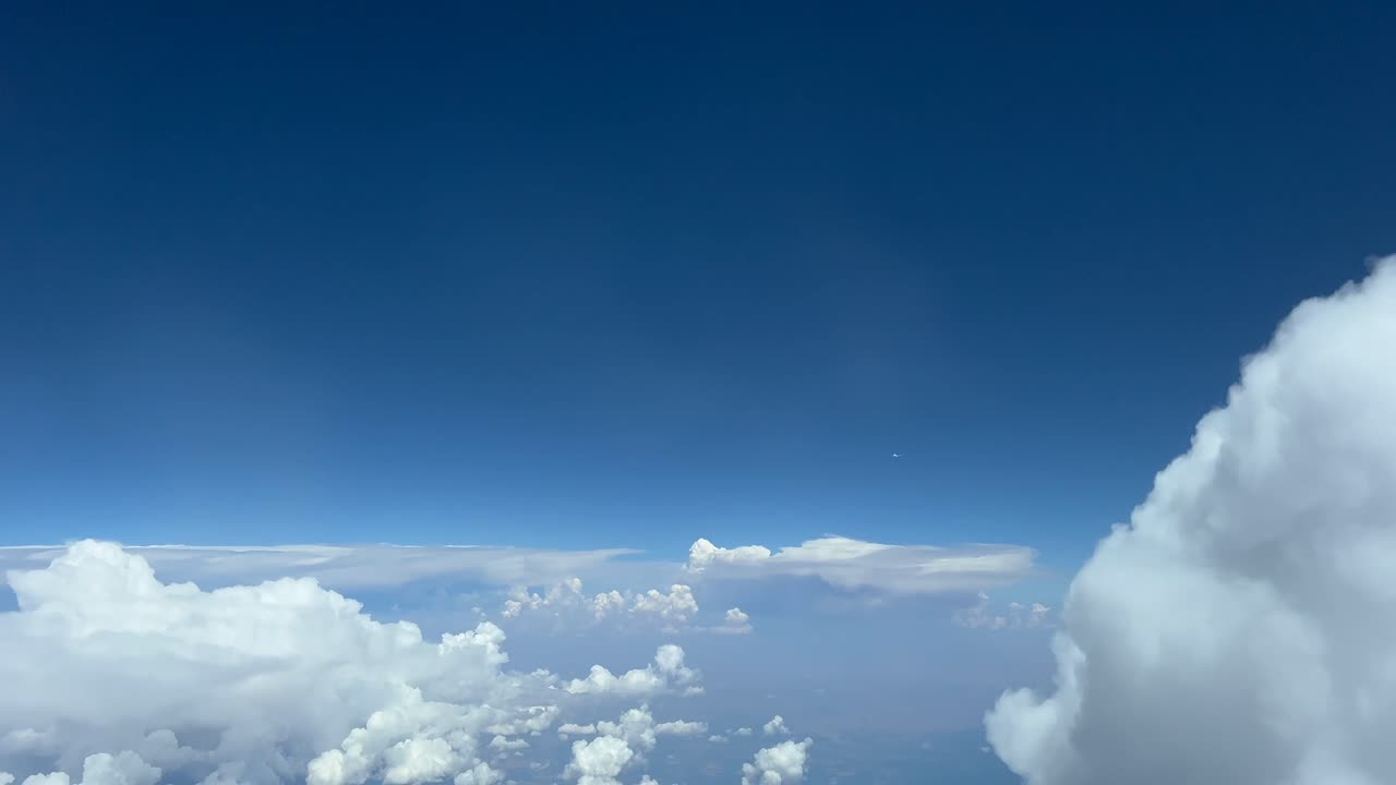 Airplane crossing as seen by the pilot of a jet airplane flying in a blue sky with some stormy clouds. Immersive pilot POV FPV. 4K 60FPS