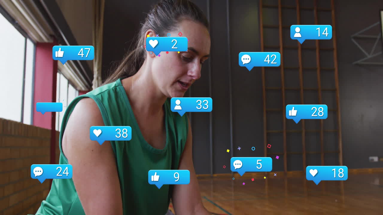 woman kneeling on gym floor, viewing floating social media marketing notification icons
