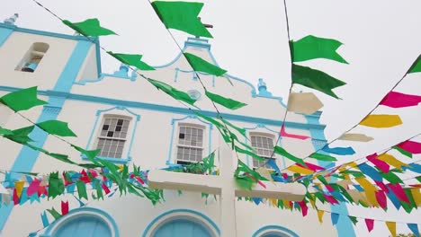 slow motion upward shot of the church of our lady of the light decorated with multicolored flags, morro de sao paulo, bahia, brazil