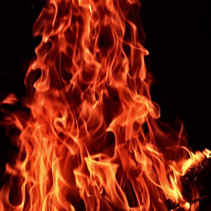 Un brasero con una llama ardiendo. Llama de hoguera brillando sobre un fondo oscuro.
