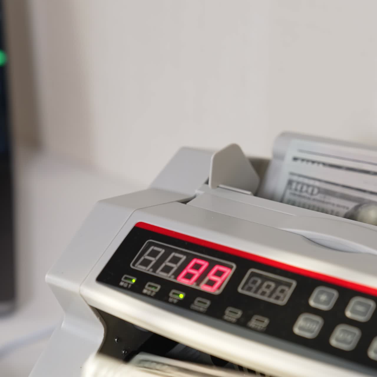 Placing hundred dollar wad into a cash machine slot. US currency disappearing quickly in the equipment. Close up