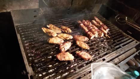 turning over chicken wings and skewers on hot charcoal barbecue and removing finished, done meat