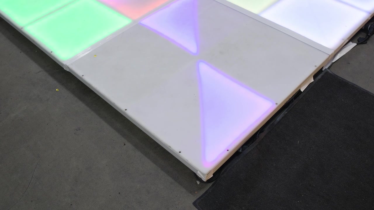 Vista ravvicinata di pannelli luminosi a pavimento che brillano di luce colorata all'interno di una sala ricevimenti per quinceañera