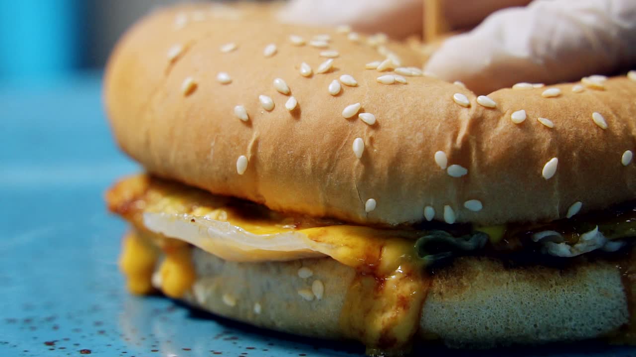 Yummy fast food concept. Fresh grilled burger bun with sesame seeds and melted cheese. Unhealthy lifestyle. Macro shot