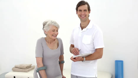 physiotherapist talking with senior patient on crutches
