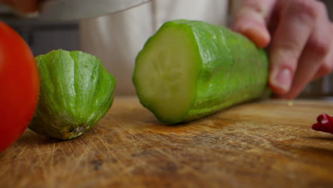 chef cutting cucumber and tomatoes
