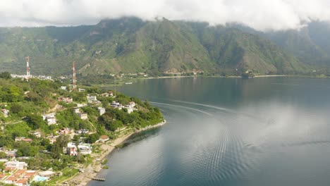 drone rises as mesmerizing patterns in water of lake atitlan guatemala vibrate below green mountains