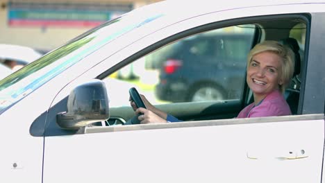 Woman-in-pink-shirt-sitting-in-a-white-car-with-a-big-smile-driving