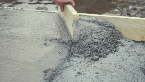 tapping flattening fresh cement with wooden board