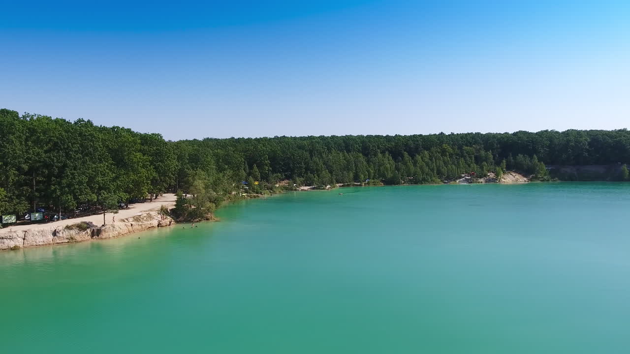 Stunning scenery of a lake made by people. Blue manmade pond at the place of former quarry and bank overgrown with trees.