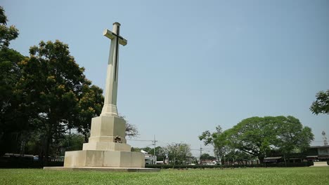 hd static shot of world war two memorial graveyard with tall crucifix monument in a peaceful cemetery in kanchanaburi, thailand