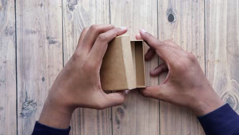 hands opening a brown cardboard gift box with a thank you note