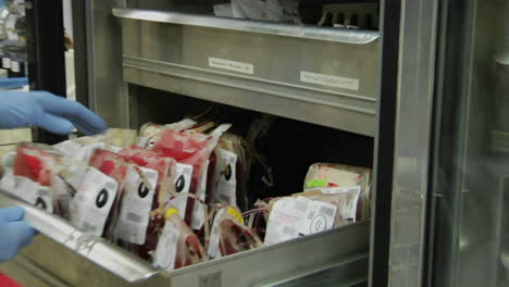 a nurse removes a bag of blood from a drawer at a blood bank 1