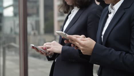 una foto cortada de mujeres de negocios usando teléfonos inteligentes