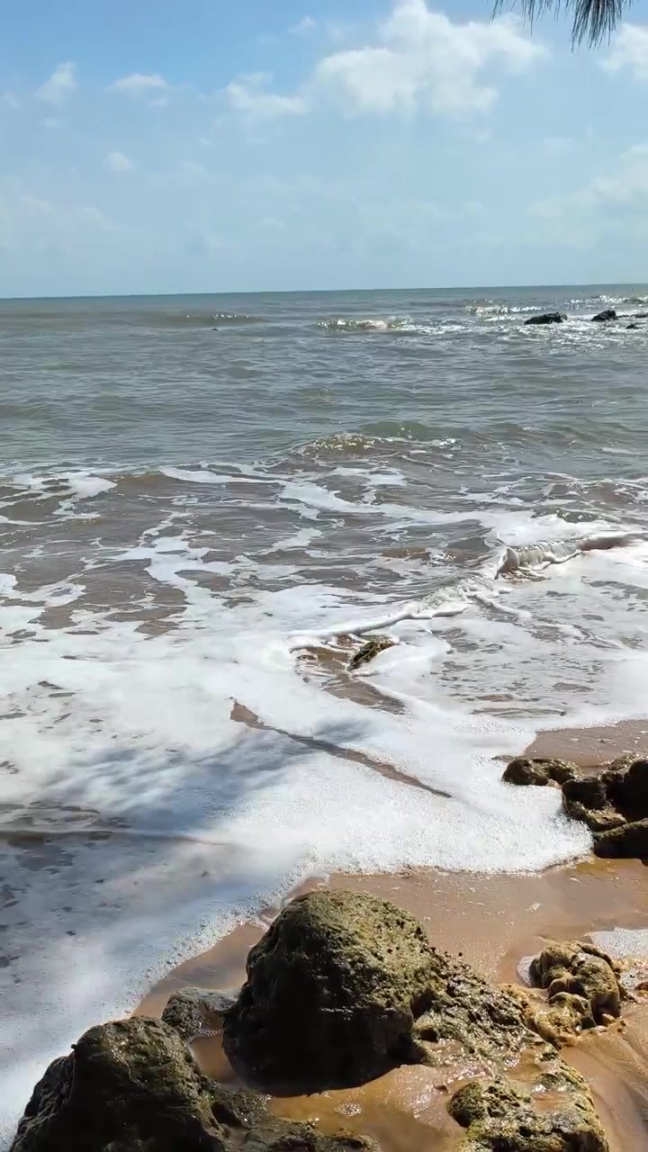 Dolci onde dell'oceano che si infrangono su una spiaggia tropicale rocciosa