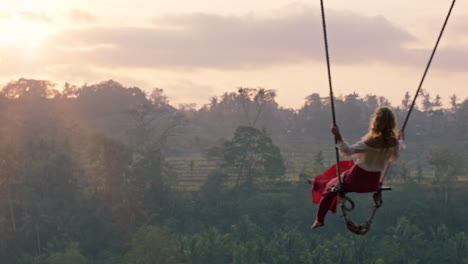 Mujer-Viajera-Balanceándose-Sobre-La-Selva-Tropical-Al-Amanecer-Turista-Sentada-En-Un-Columpio-Con-Vista-Panorámica-Disfrutando-De-La-Libertad-En-Vacaciones-Divirtiéndose-Estilo-De-Vida-De-Vacaciones-En-Cámara-Lenta