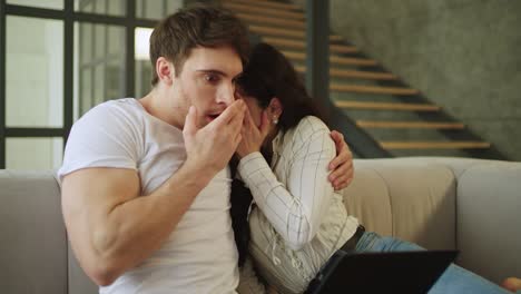 hombre y mujer conmocionados expresando miedo mientras miraban la computadora portátil.
