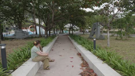 a young caucasian woman in her early 30s sitting on a wall in con dao island park, vietnam