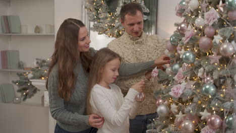 familia feliz decora el árbol de navidad con bolas y adornos