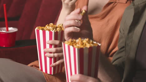 close up view of couple hands holding popcorn in the cinema 1