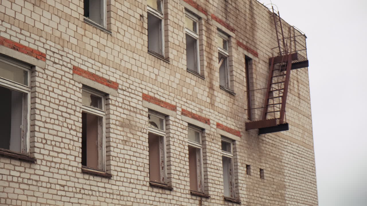 viejo edificio de ladrillo abandonado con ventanas rotas y escalera de incendios
