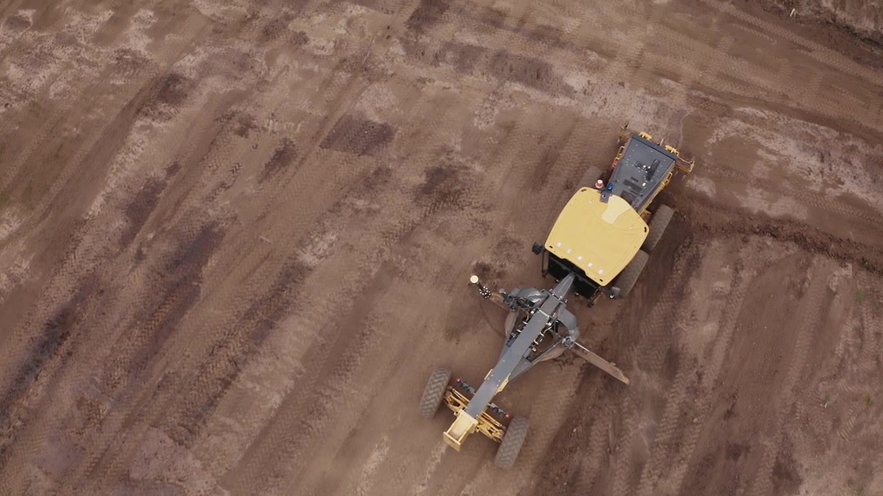 Aerial video of development project earthworks project with heavy machinery grader in action