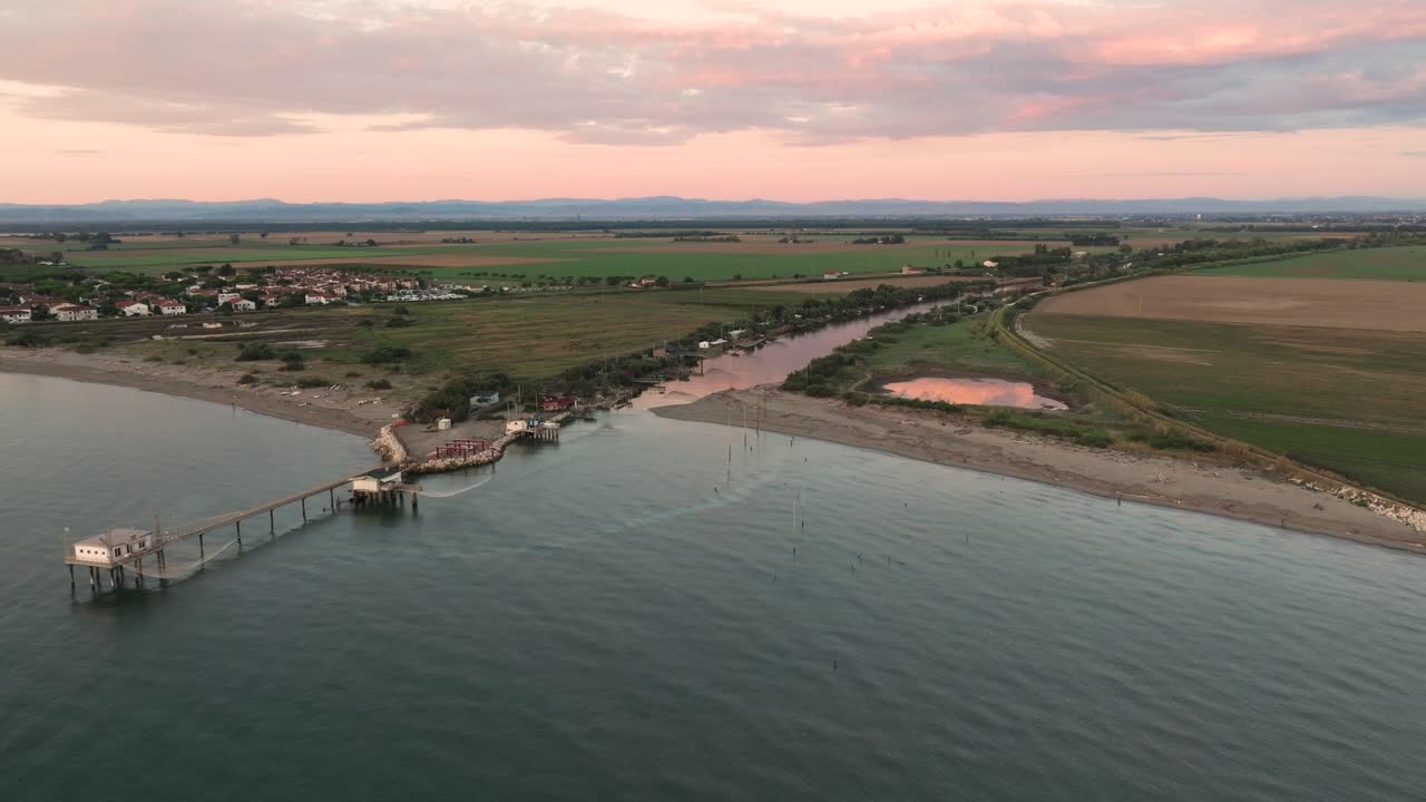vista aérea de cabañas de pesca a orillas del estuario al atardecer, máquina de pesca italiana, llamada "trabucco", lido di dante, ravenna cerca del valle de comacchio