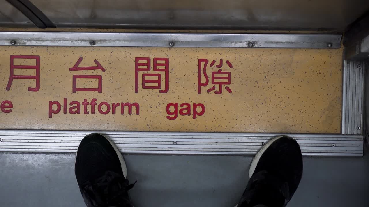 한 사람이 기차 차량의 문 앞에 서 있습니다. 근접 발. 중국어 단어는 플랫폼 간격에 주의를 기울이십시오. 기차가 움직이고 카메라가 흔들립니다. 주체는 오른쪽에 있습니다.