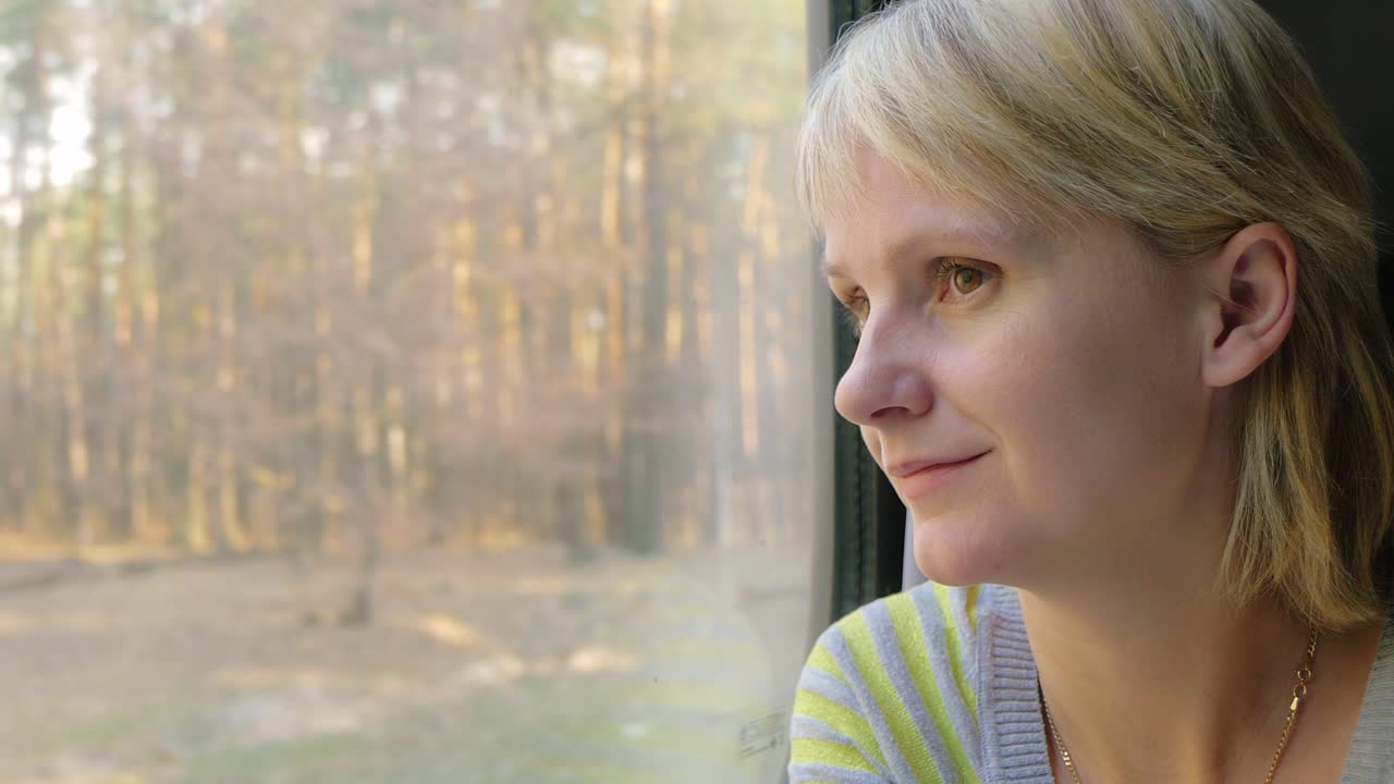 retrato de una mujer joven que viaja en un tren mirando por la ventana los rayos del sol la iluminan